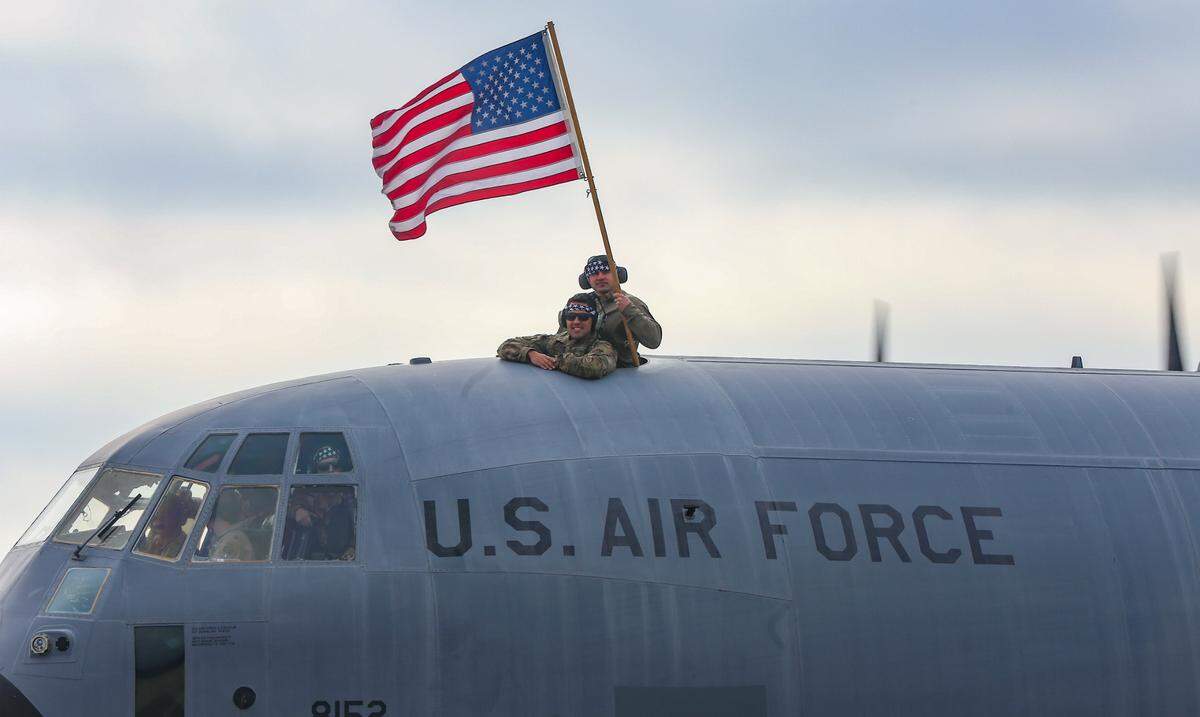 Airmen from the 815th Airlift Squadron wave an American flag outside of the top of a C-130J as four planed filled with airmen and maintenance and support throughout the 403rd Wing return to Keesler Air Base Saturday, Feb. 13, 2021 after a five-month deployment to Southwest Asia. 