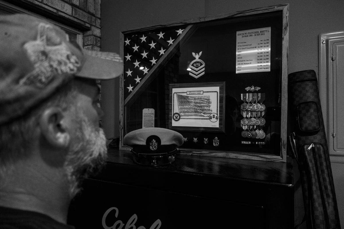 Brett in front of a shadow box displaying an American flag and medals.