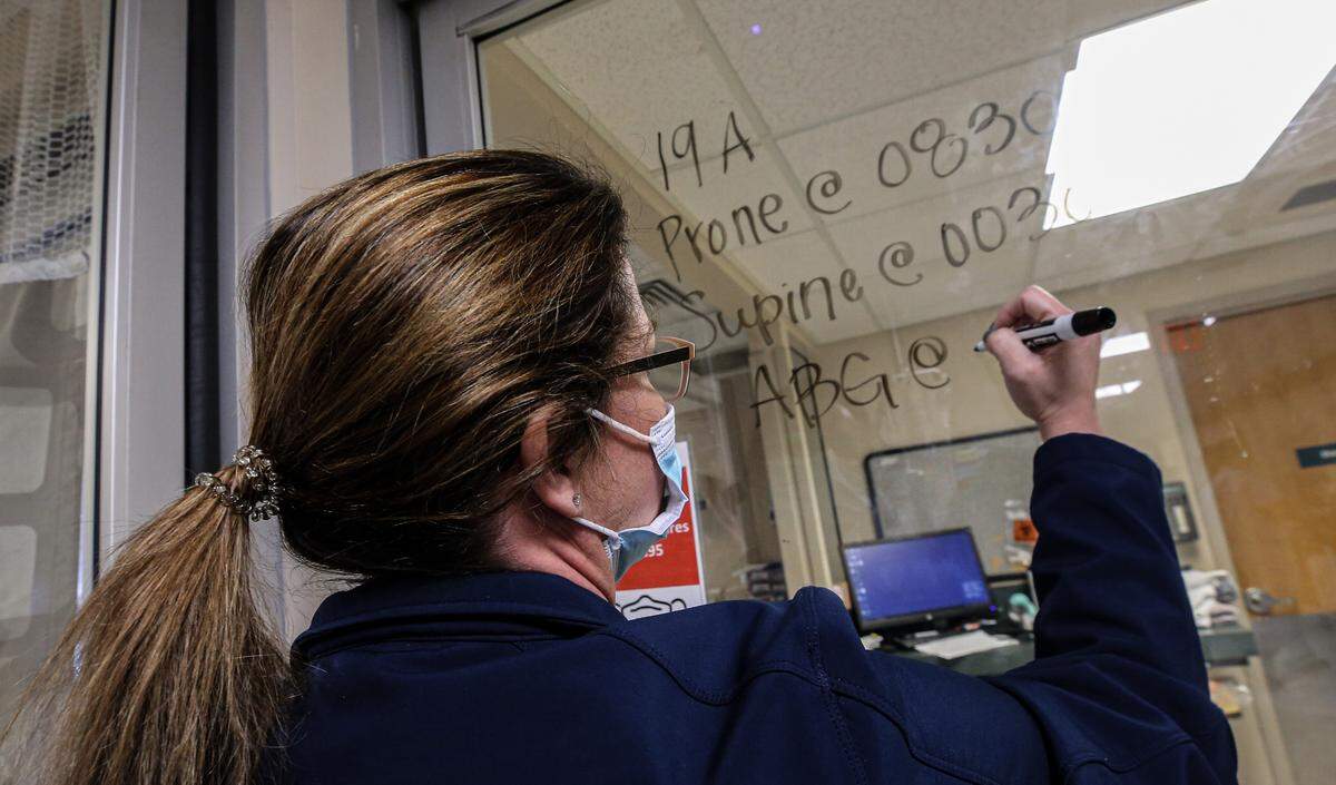 Memorial Hospital registered nurse Miranda Lewis writes the proning schedule for a COVID-19 patient in the intensive care unit January 25, 2021. Proning is a practice staff uses to help patients breathe better by turning them on their stomachs.