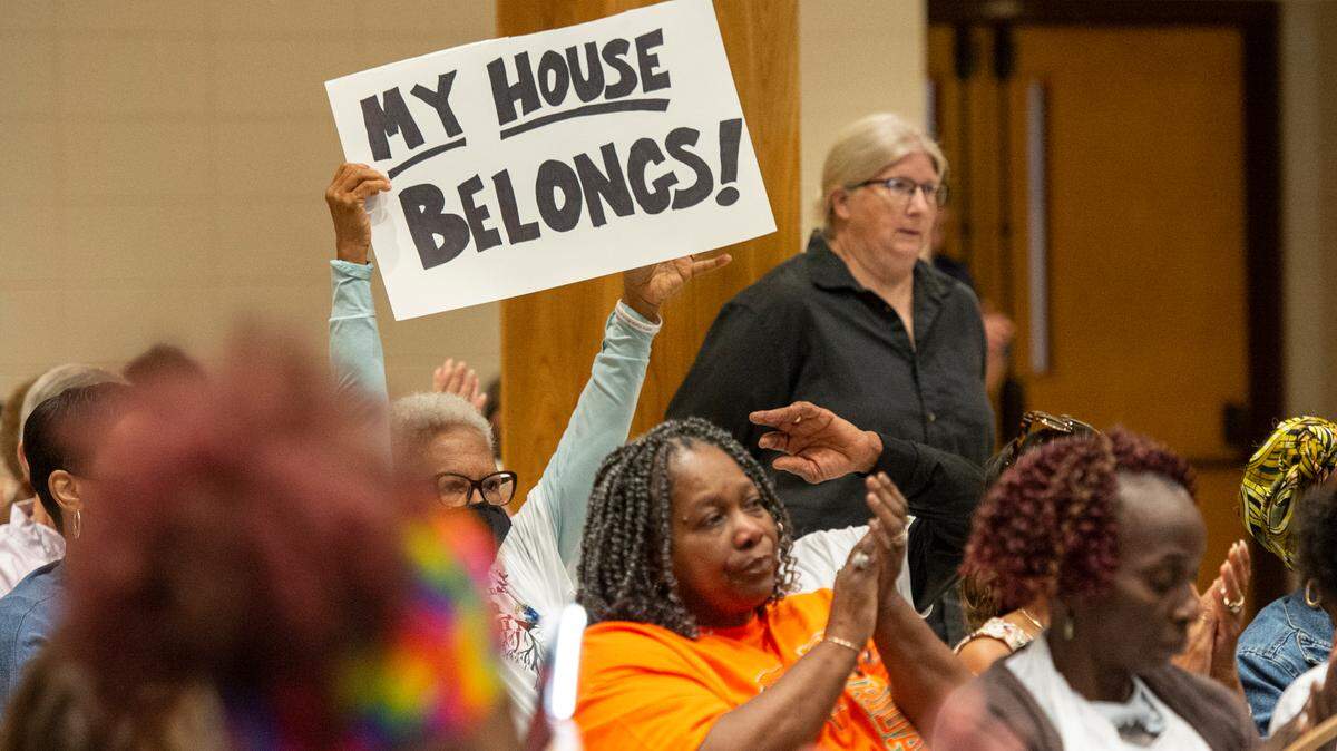 Ocean Springs residents and members of We Shall Not Be Moved, an organization against a proposed Urban Renewal Plan, raise signs as residents voice their concerns about the plan during a public hearing hosted by the mayor and Board of Aldermen at the Ocean Springs Civic Center on Monday, Oct. 2, 2023.