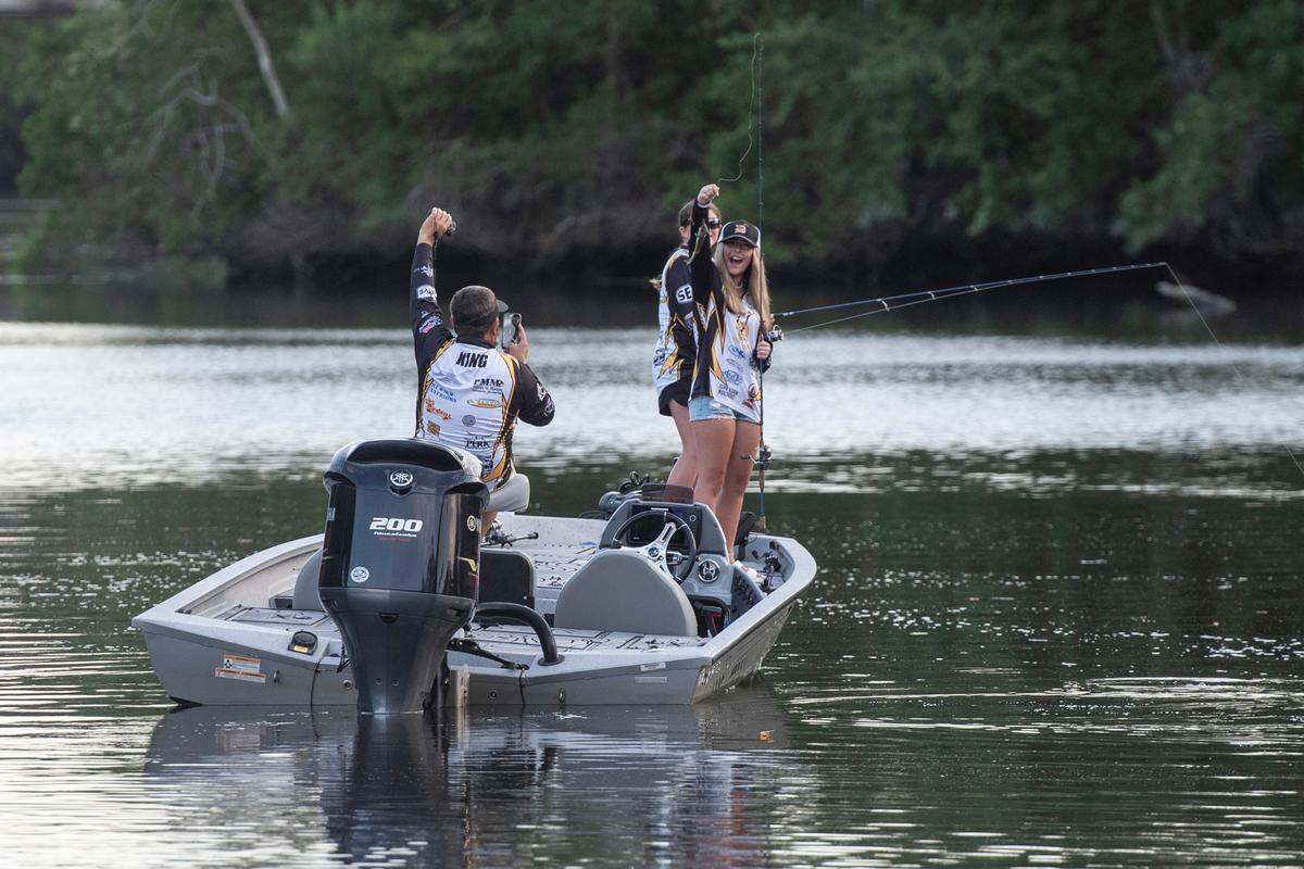 Coach Hiram King takes a photo as D’Iberville Bass Fishing Team member Harper Krohn catches a fish while fishing on the Tchoutacabouffa River in D’Iberville with her teammate Olivia King on Monday, June 3, 2024.