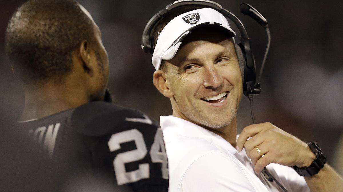 FILE - In this Aug. 28. 2014, file photo, then-Oakland Raiders coach Dennis Allen smiles as he talks with cornerback Charles Woodson during the second quarter of an NFL preseason football game against the Seattle Seahawks, in Oakland, Calif. Saints coach Sean Payton promised changes were coming to his sagging defense. He started by firing defensive coordinator Rob Ryan. Senior defensive assistant Dennis Allen will assume Ryan's duties. The move, announced Monday night, Nov. 16, 2015, on Payton's weekly radio show on WWL-AM, comes a day after the Saints allowed 526 yards in a 47-14 loss to the Washington Redskins. (AP Photo/Ben Margot, File)