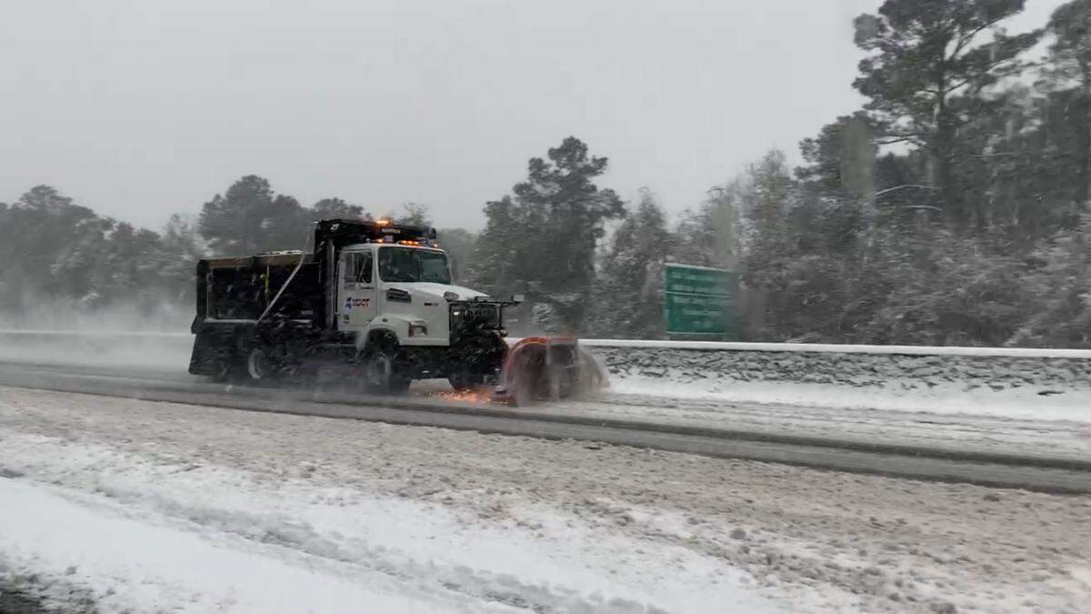 A snowplow clears snow and ice from Interstate 10 in Gulfport, which remained open Wednesday.