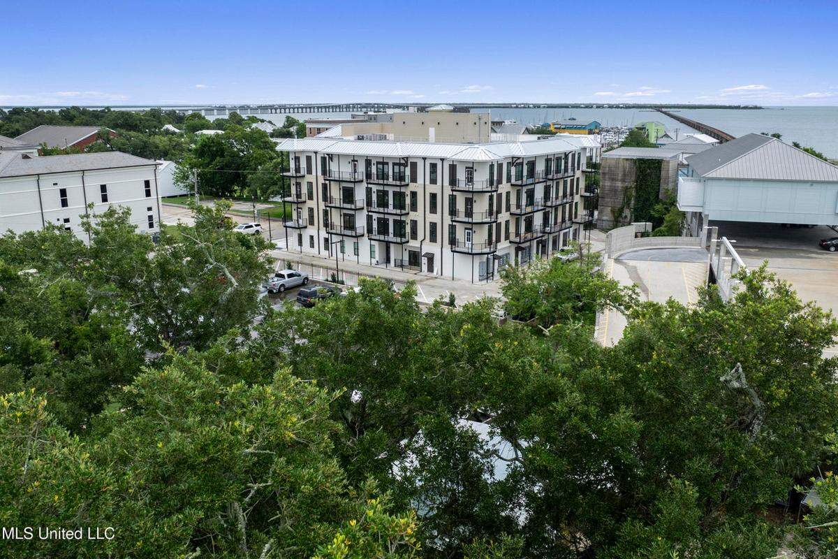 An aerial view shows how 124 Court Condominiums in Bay St. Louis has views of downtown Bay St. Louis and its tree cover and white beach.