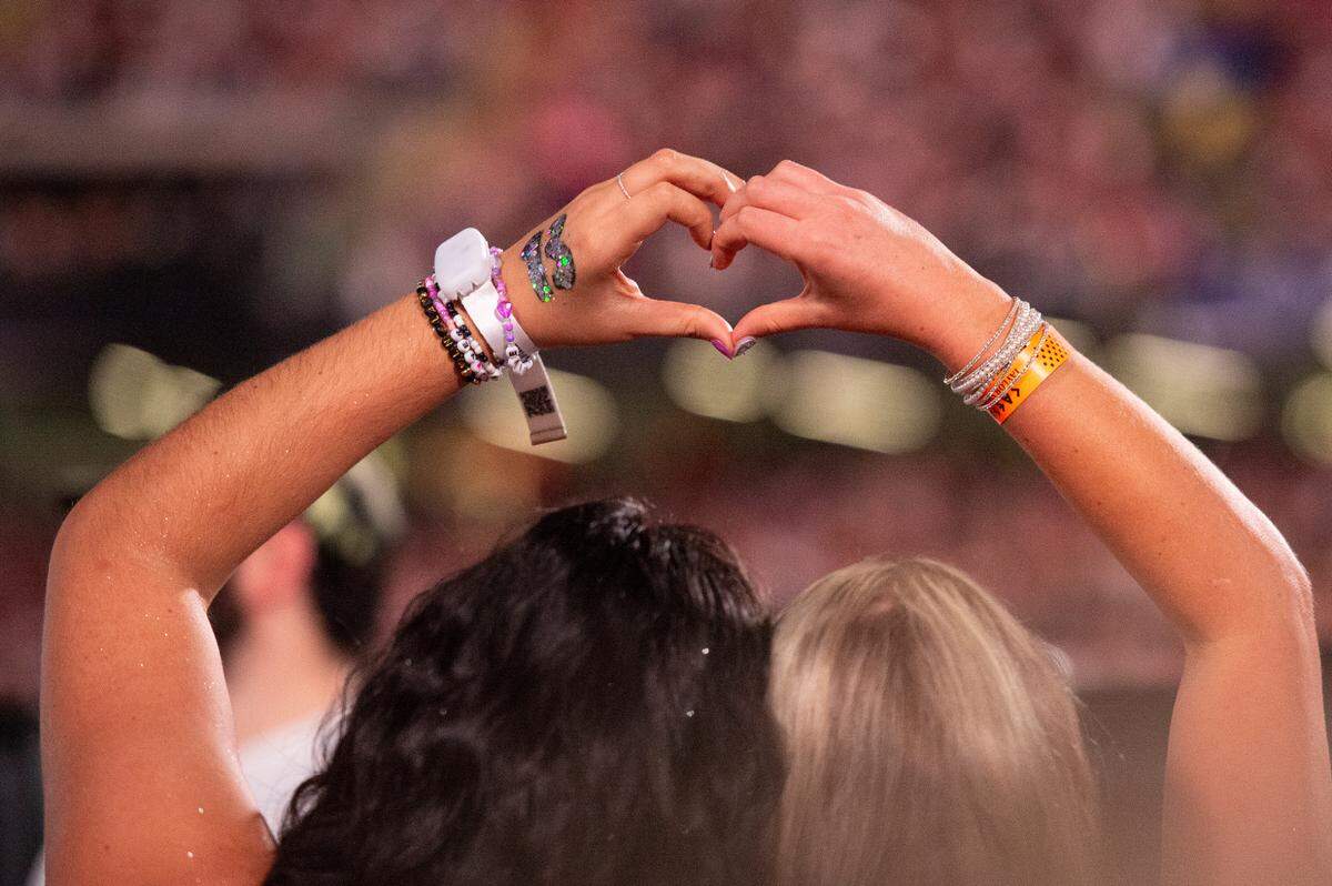 Fans make heart hands for a photo before the start of Taylor Swift’s The Eras Tour at the Cesars Superdome in New Orleans on Friday, Oct. 25, 2024.
