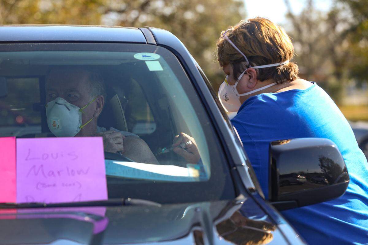 Steve Tingle, 76, is given the Moderna coronavirus vaccine during a drive-up appointment with Coastal Family Health Clinic on Wednesday, Jan. 13, 2021.