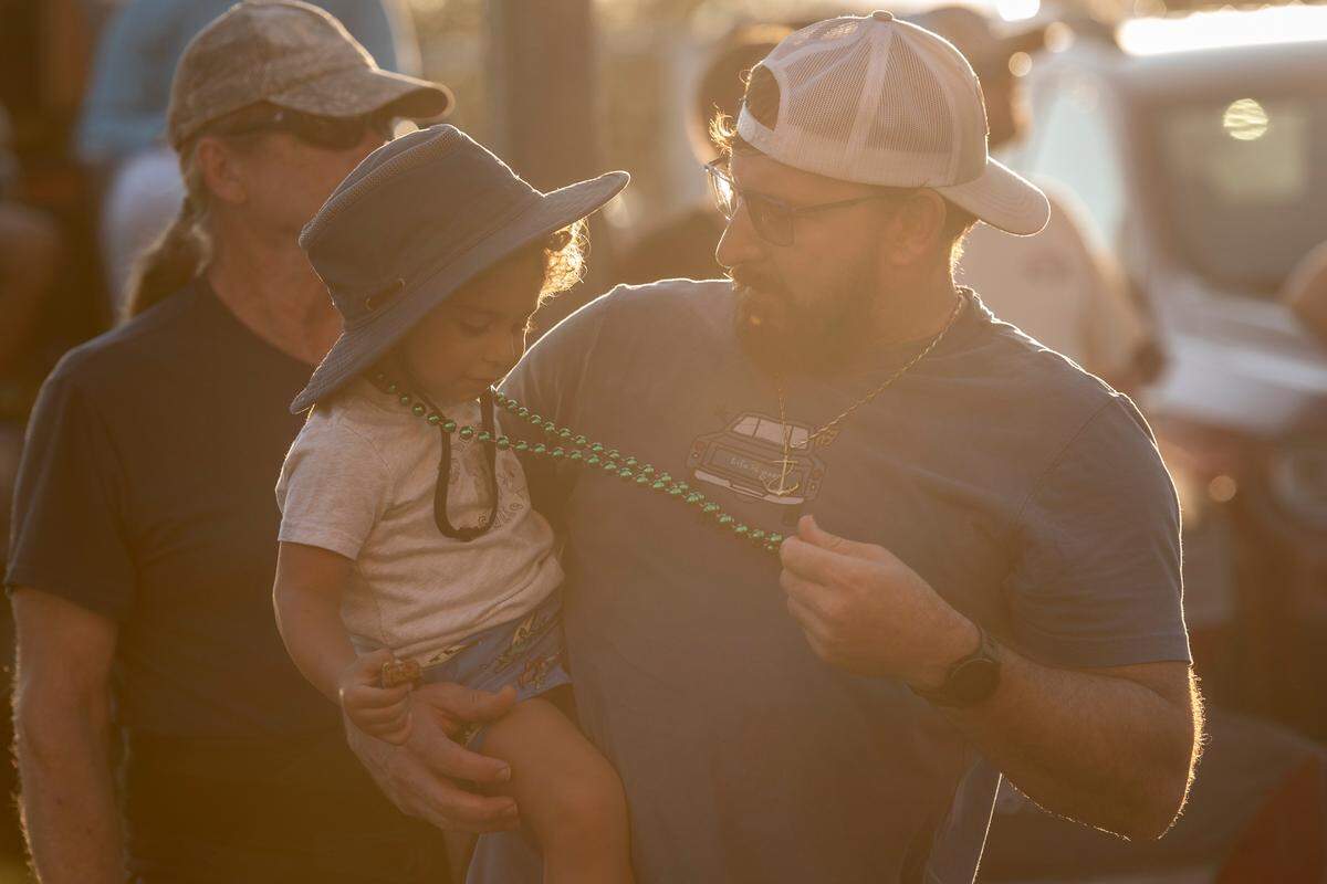A spectator gives a child beads during the Long Beach Parade in Long Beach, one of the events in Cruisin’ The Coast, on Monday, Oct. 7, 2024.