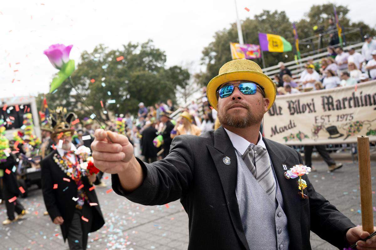 A member of the Ole Biloxi Marching Club hands out flowers to members of the crowd during the Gulf Coast Carnival Association’s Fat Tuesday parade in Biloxi on Tuesday, Feb. 17, 2026.