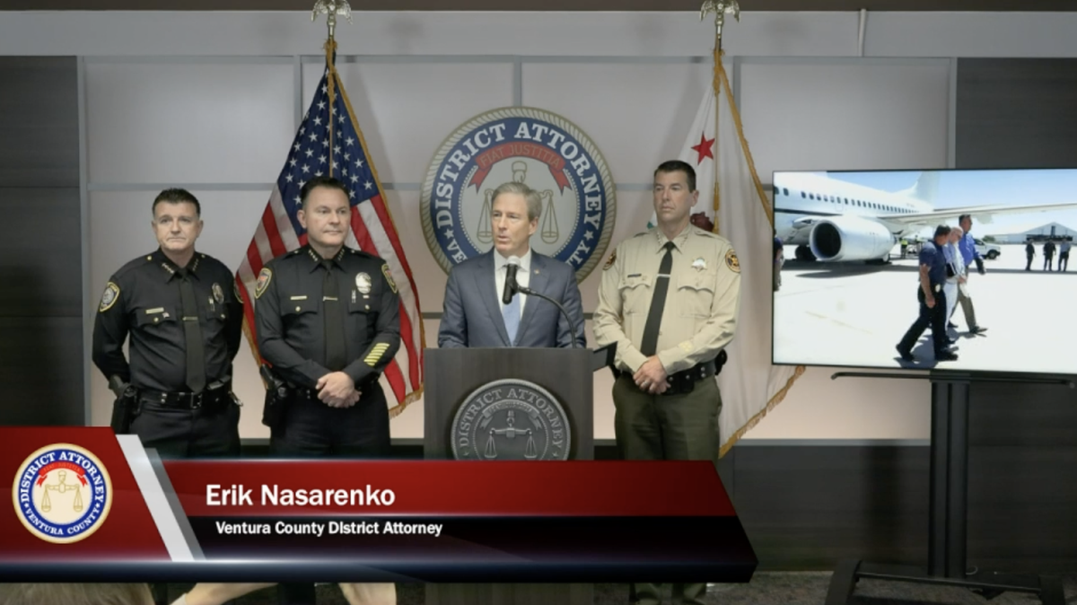 The Ventura County District Attorney speaks at a news conference before a screen that shows the extradition of Warren Luther Alexander, who is accused in the murders of three women in 1977.