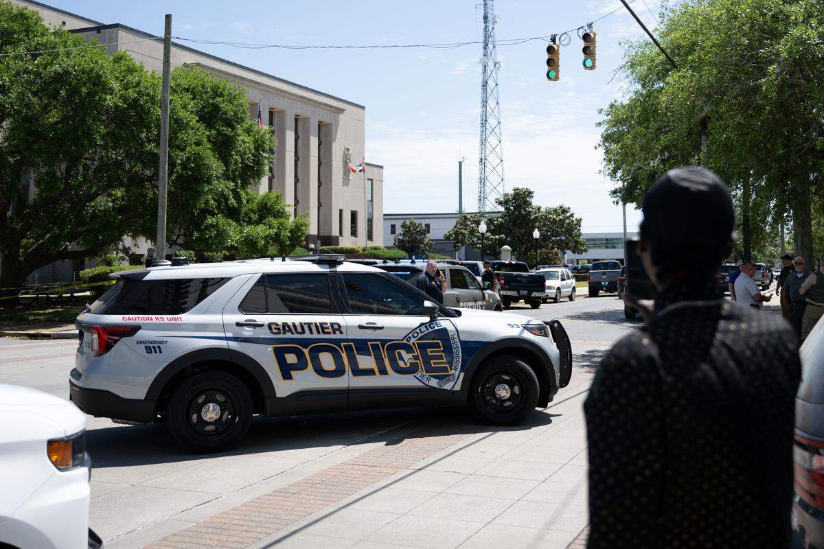 Police cars and pedestrians gather outside the Jackson County Courthouse in Pascagoula after a shooting on Thursday, April 16, 2026.