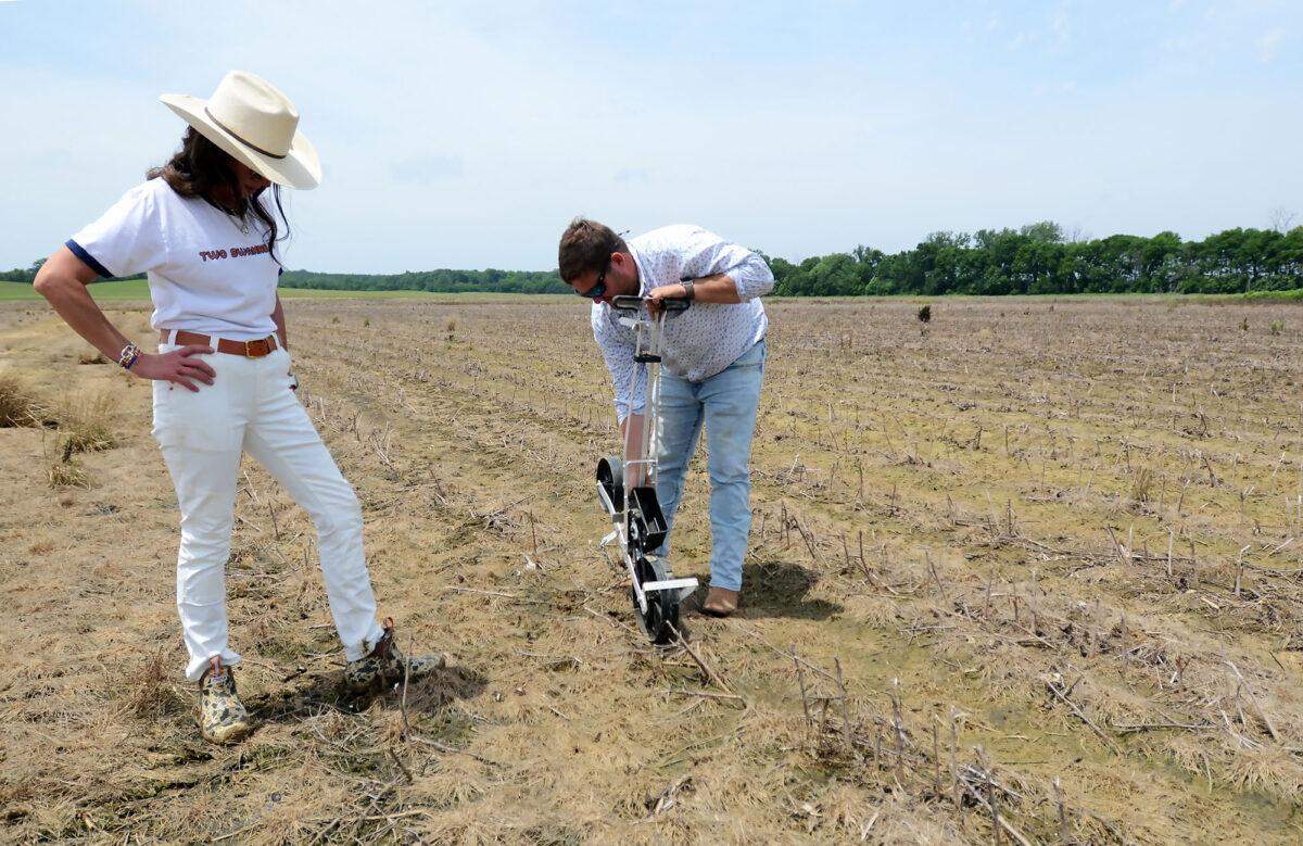 Husband-and-wife farmers Rhett and Lauren Swann of New Albany demonstrate, using a one-row push planter, how their cotton fields are too muddy for planting, Thursday, May 15, 2025.