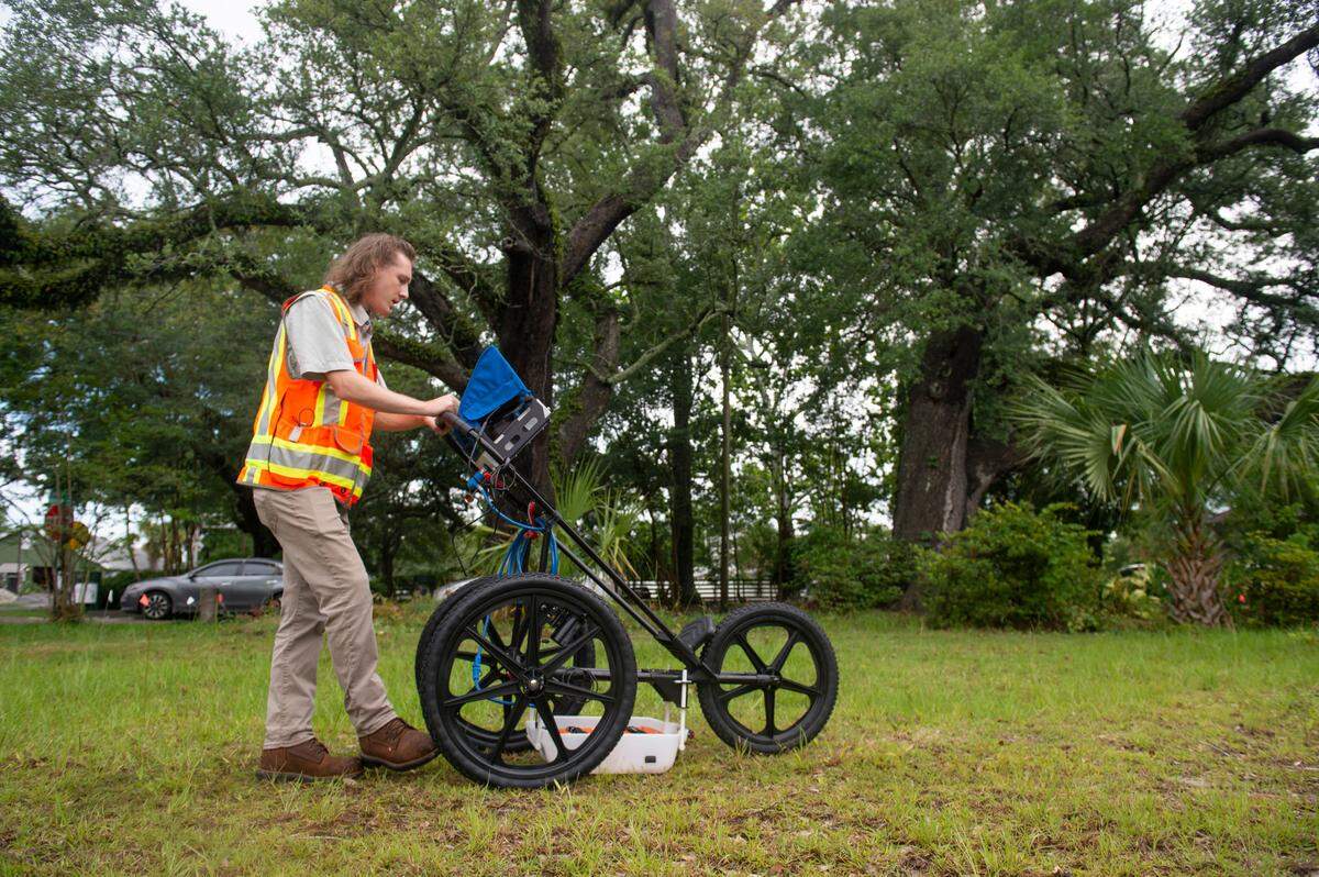 Clayton Fulgham pushes a radar that can penetrate the ground around the base of a live oak tree on a property in Ocean Springs on Thursday, May 26, 2022. The radar is used to map out tree root systems in order to help construction companies avoid disrupting the roots. This study was done before The Pullman House luxury townhouses were built.