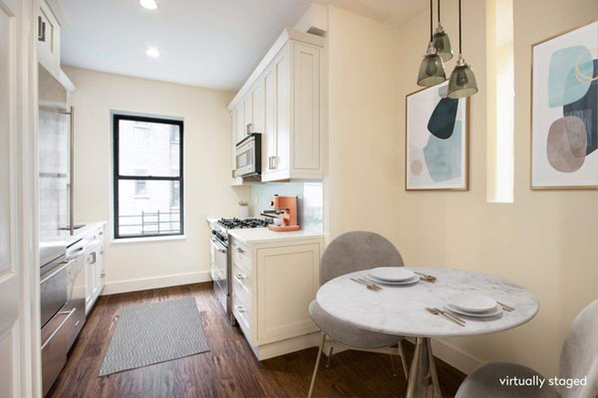 The renovated kitchen space features bright white cabinetry, glass-tiled back splash and custom countertops, according to the listing.