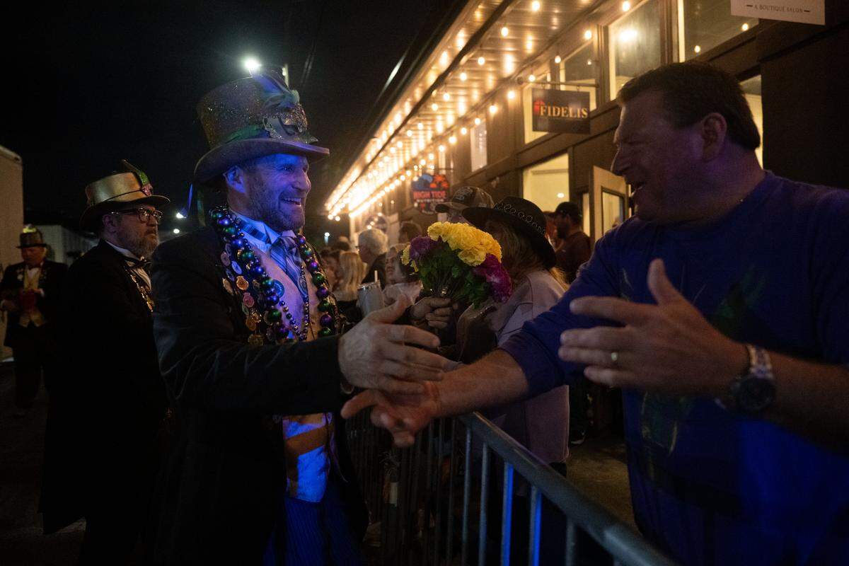 Parade participants pass out flowers to attendees during the Krewe of Neptune parade in Biloxi on Saturday, Feb. 14, 2026.