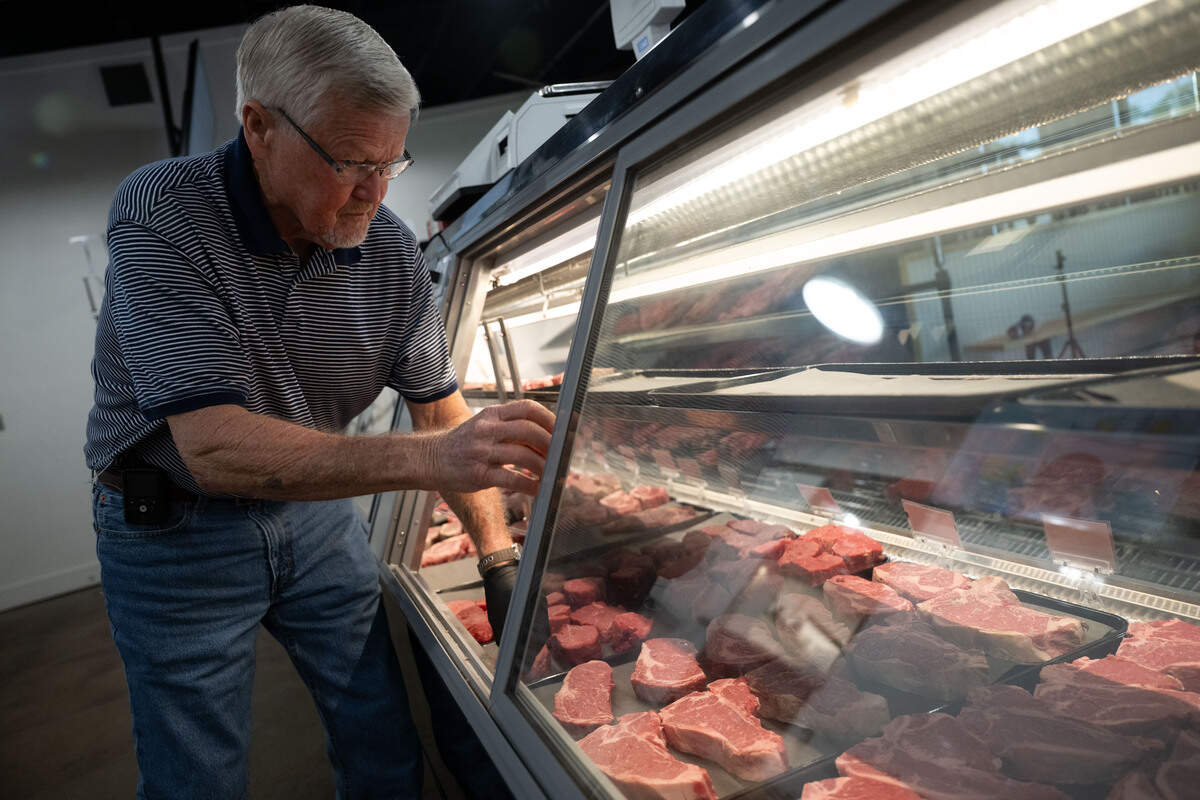 Gil Tynes places steaks into a glass display at Johnny Pizmo’s Butchery and Marketplace in Gulfport.