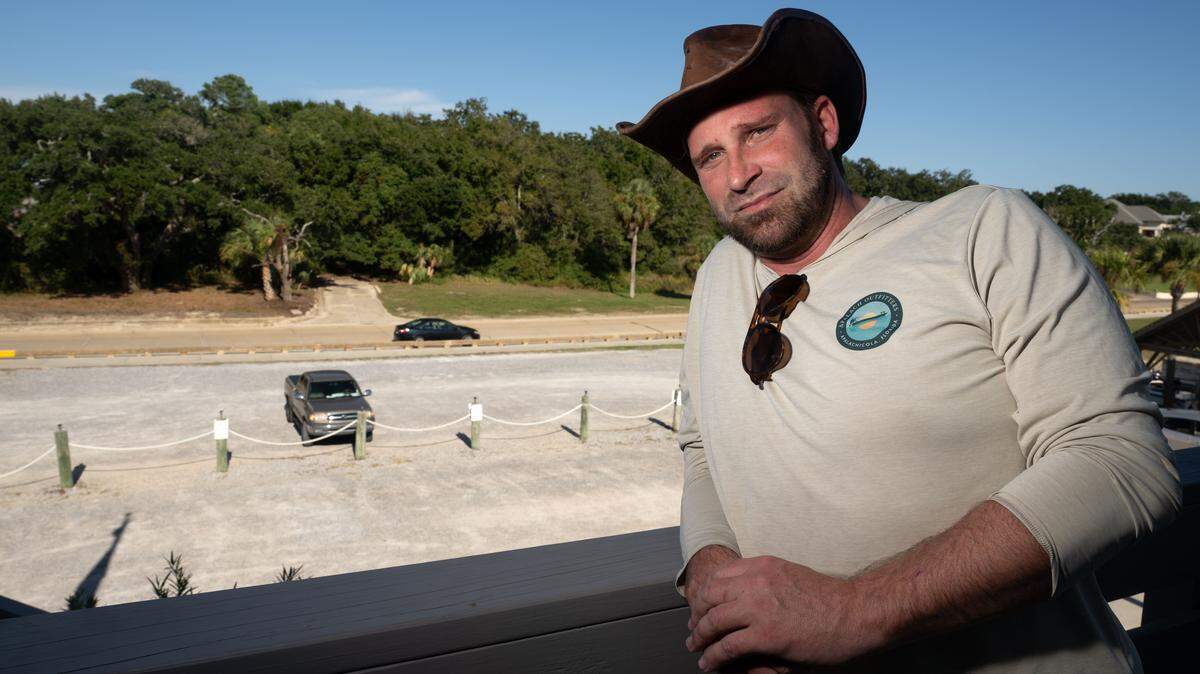 Realtor Brad Jay poses for a photo at the Ocean Springs Yacht Club in front of a forested lot that he has a contract to buy, with plans for a botanical garden and family friendly development, including a miniature golf course.