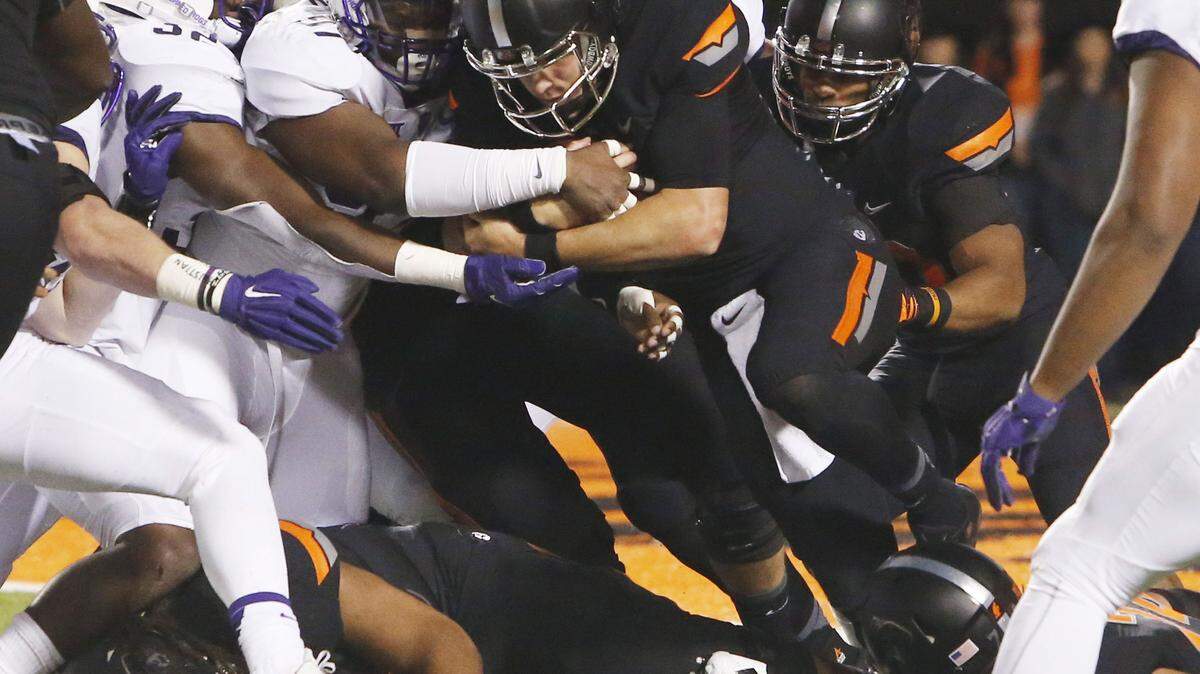SUE OGROCKI/ASSOCIATED PRESS 
 Oklahoma State quarterback Mason Rudolph, center, drives up the middle against TCU. Rudolph is one of two quarterbacks the Cowboys will play against Ole Miss in the Sugar Bowl on Friday.