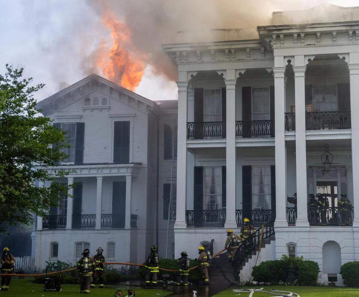 Firefighters run a line through the part of the Nottoway Plantation as fire breaks through the roof of the South wing on Thursday, May 15, 2025 in White Castle, Louisiana.