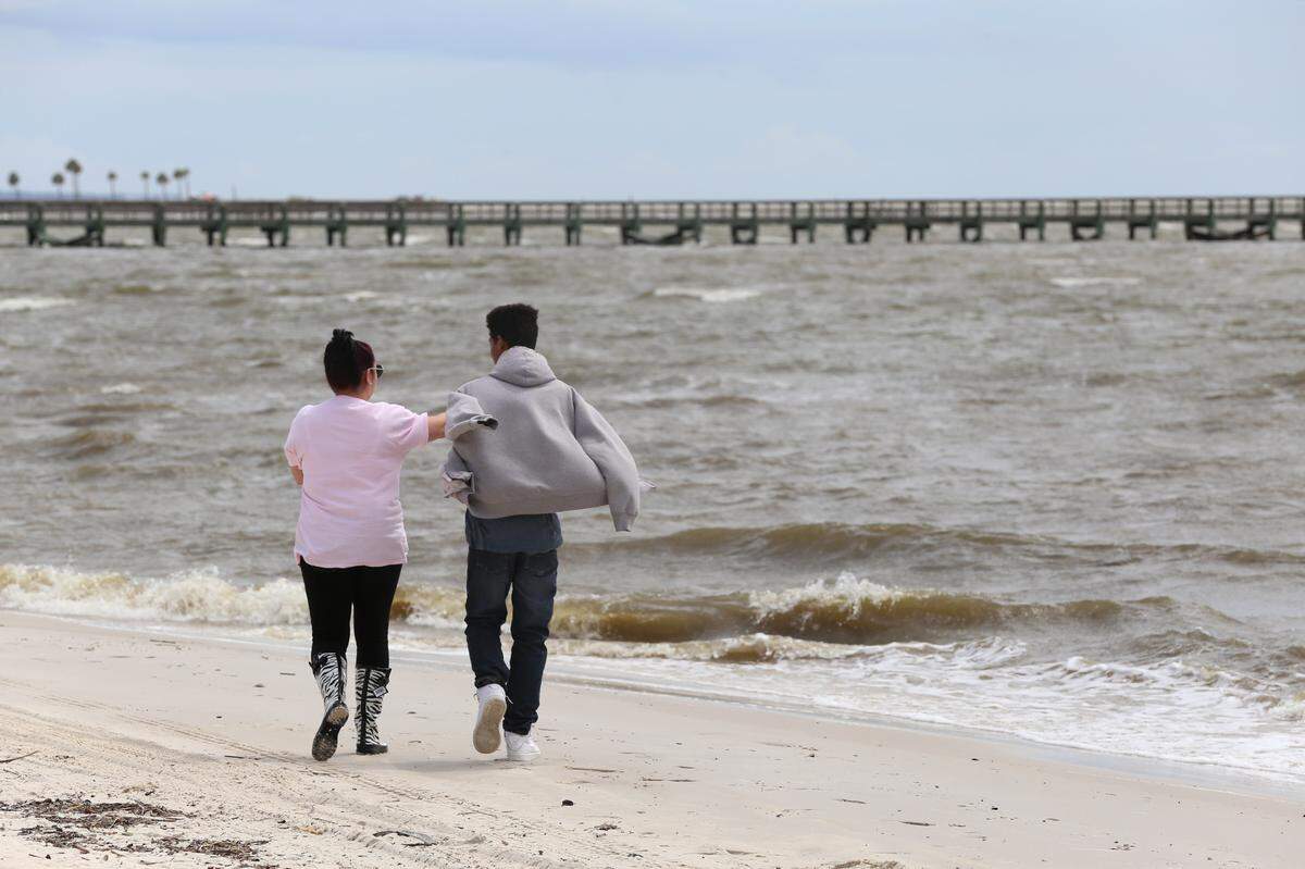 Krystal Flanagan, left, of Biloxi and her son, Desmond Dentley, walk on the beach in Biloxi on Tuesday, Sept. 4, 2018 as Tropical Storm Gordon heads toward the Mississippi coast. The storm could strengthen to a category 1 hurricane before making landfall later on Tuesday.