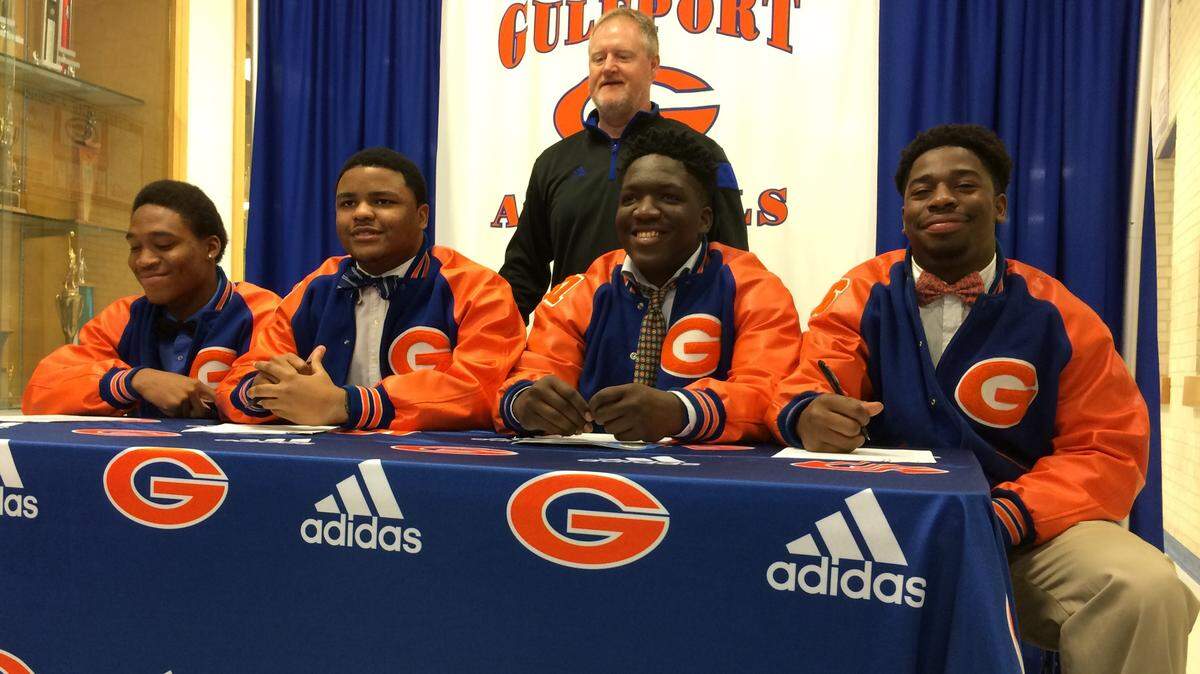 PATRICK MAGEE/SUN HERALD 
 Gulfport coach Eddie Pierces watches from the back as (from left to right) Alton Conerly, Adarius Craft, Stephon Cooper and Deon Cole sign their National Letters of Intent Wednesday at Gulfport High School.