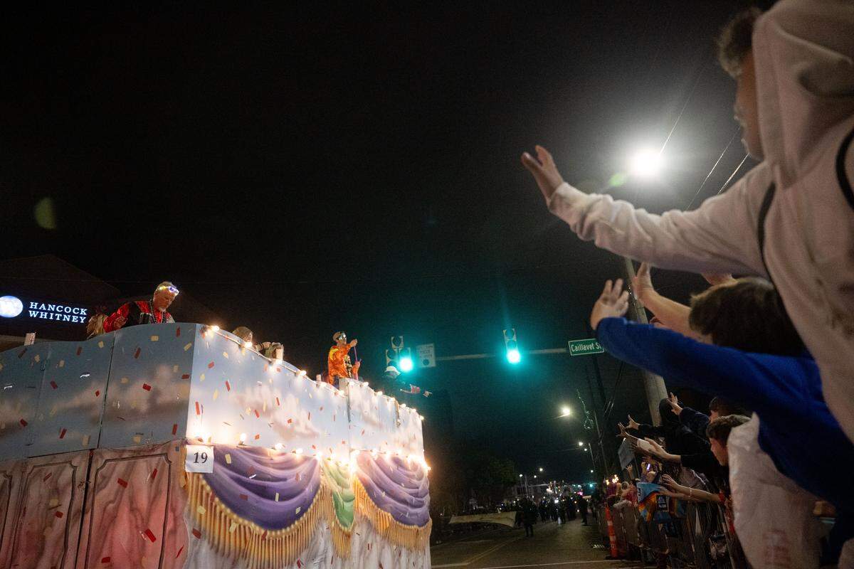 Parade attendees reach out for pride throws during the Krewe of Neptune parade in Biloxi on Saturday, Feb. 14, 2026.