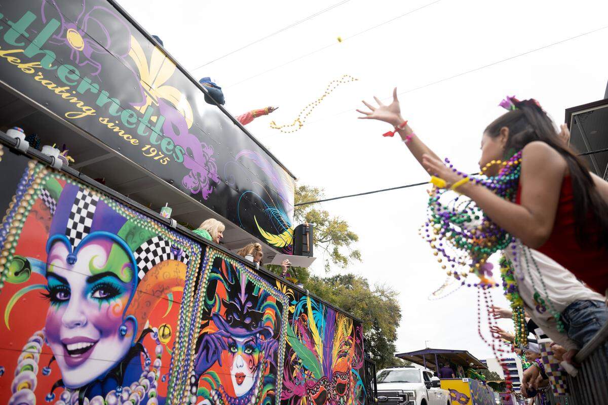 Crowd members reach out to catch Mardi Gras beads.