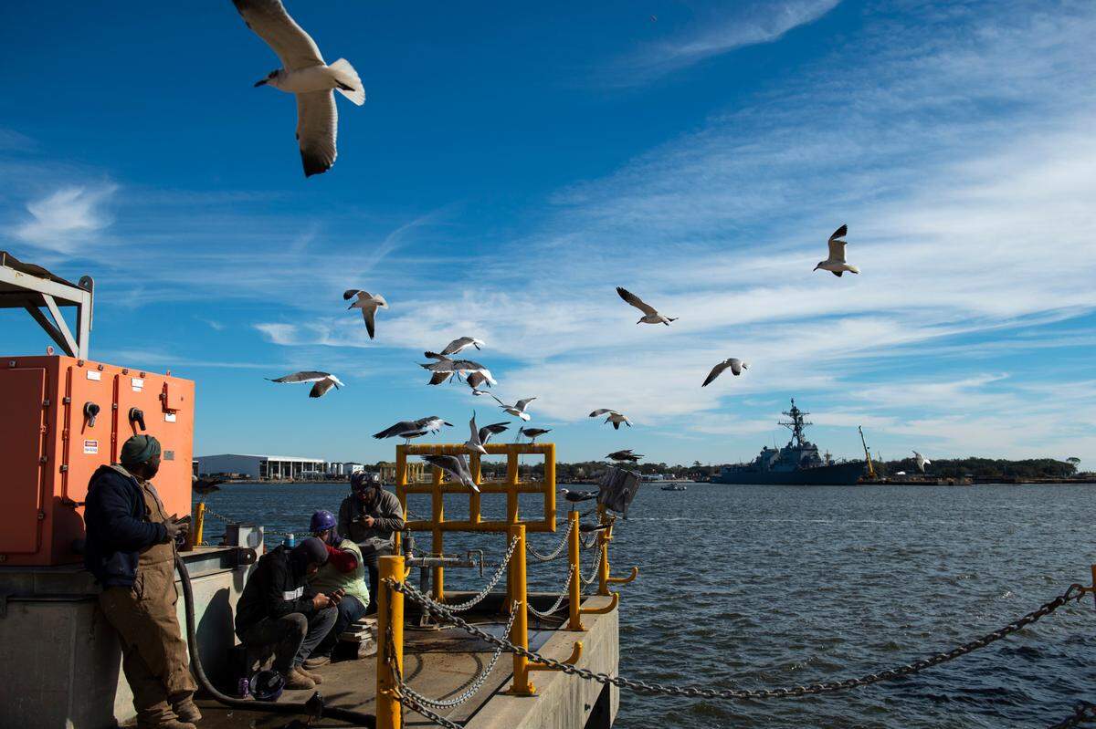 Shipyard workers take a break near a dock overlooking guided missile destroyer USS Frank E Petersen Jr. (DDG 121) at Ingalls Shipbuilding in Pascagoula on Wednesday, Jan. 26, 2022.