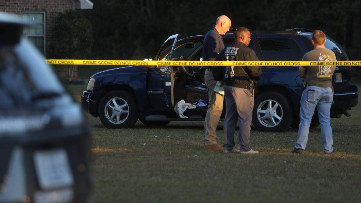 Members of the Mississipp Bureau of Investigation and the Jackson County Sheriff’s Office stand near a blue SUV that came to a stop in the front yard of a residence on Old Biloxi Road in the Latimer Community after a police pursuit on October 19, 2022.