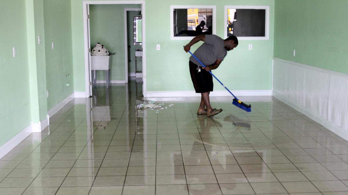 TIM ISBELL/SUN HERALD 
 Antonio Barnes sweeps water out of Melissa's Bakery on Dedeaux Road in Gulfport on Thursday. The bakery was flooded by Thursday mornings torrential rain.