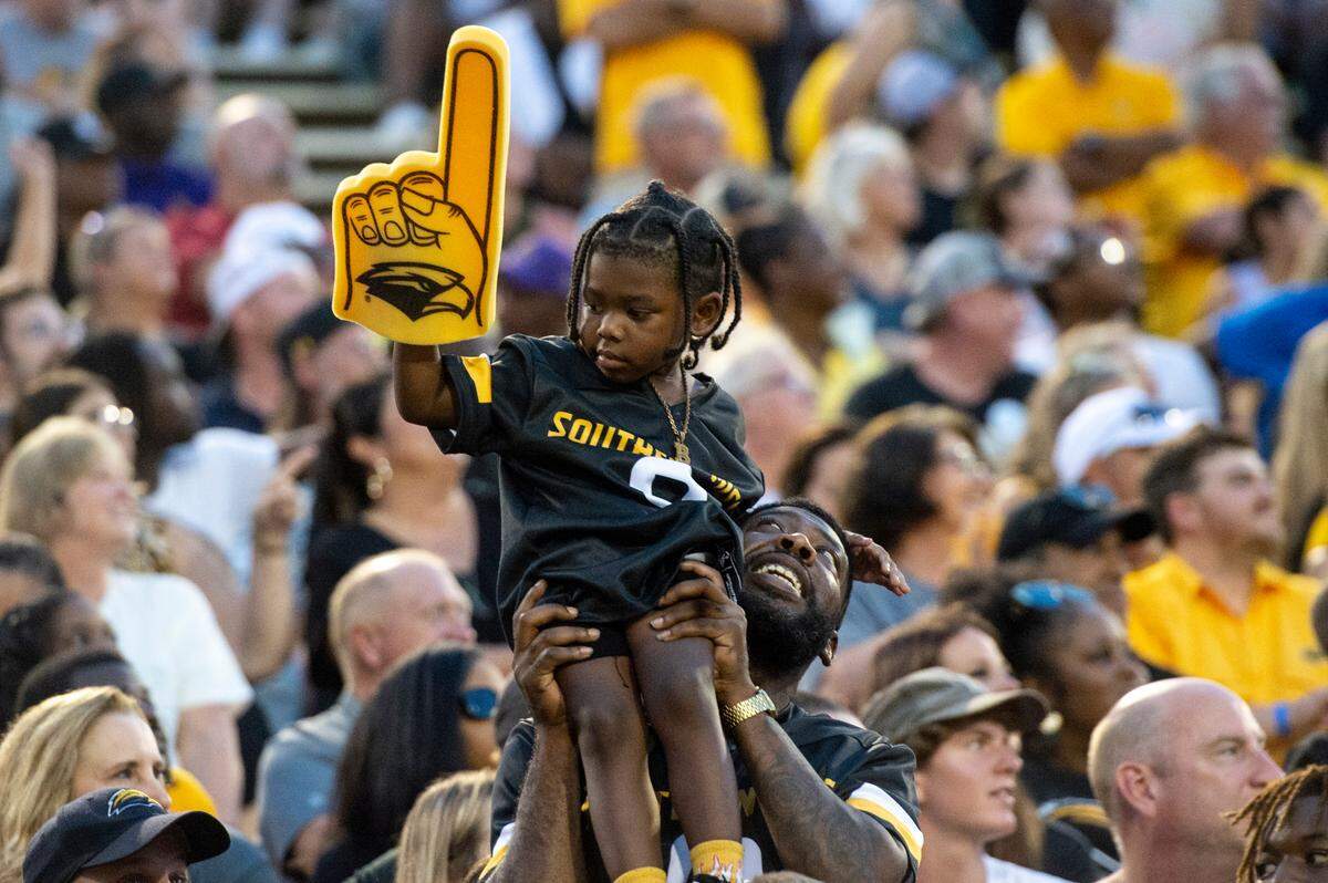 A fan holds up a child during a Southern Miss game at M.M. Roberts Stadium in Hattiesburg on Saturday, Sept. 2, 2023.