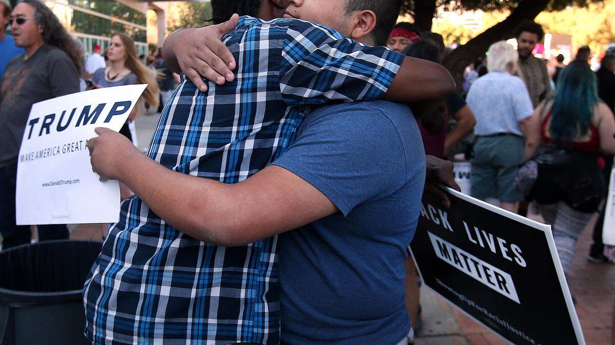 Jesus Sanchez, right, a Donald Trump supporter, hugs Leon Powell, a Trump protester after the Republican presidential candidate's rally at the Tucson Arena in downtown Tucson, Ariz., Saturday, March 19, 2016. (Mike Christy/Arizona Daily Star via AP) MANDATORY CREDIT