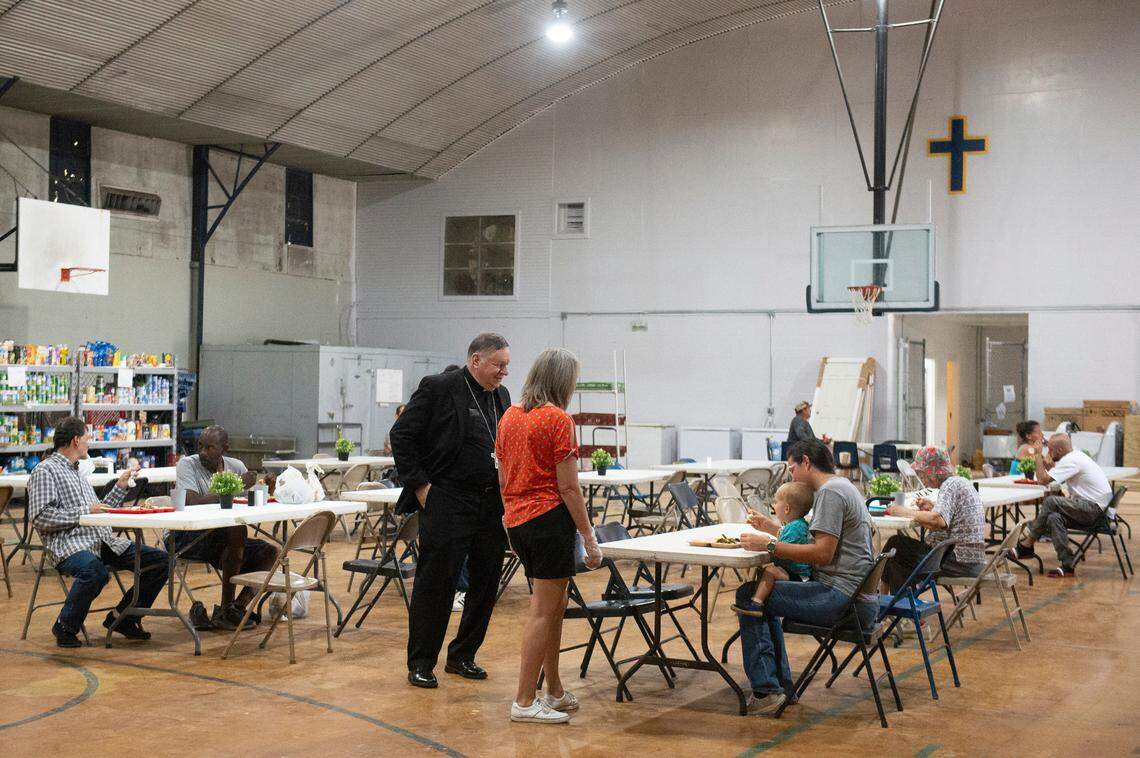 Bishop Louis F. Kihneman III visits with volunteers and people eating lunch provided by Loaves and Fishes at the former Mercy Cross High School in Biloxi on Tuesday, May 14, 2024.