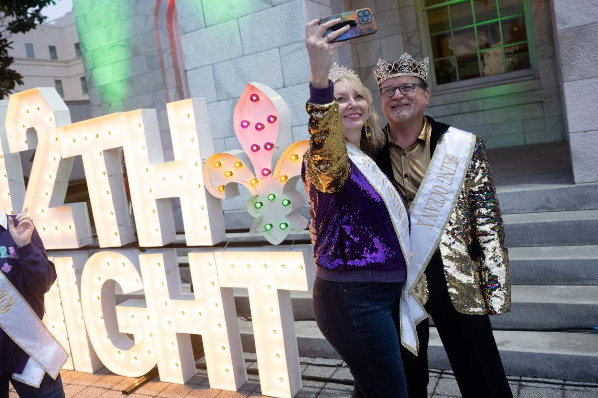 Parade attendees pose for photos in front of a sign during a 12th Night Celebration in Biloxi on Monday, Jan. 5, 2026.
