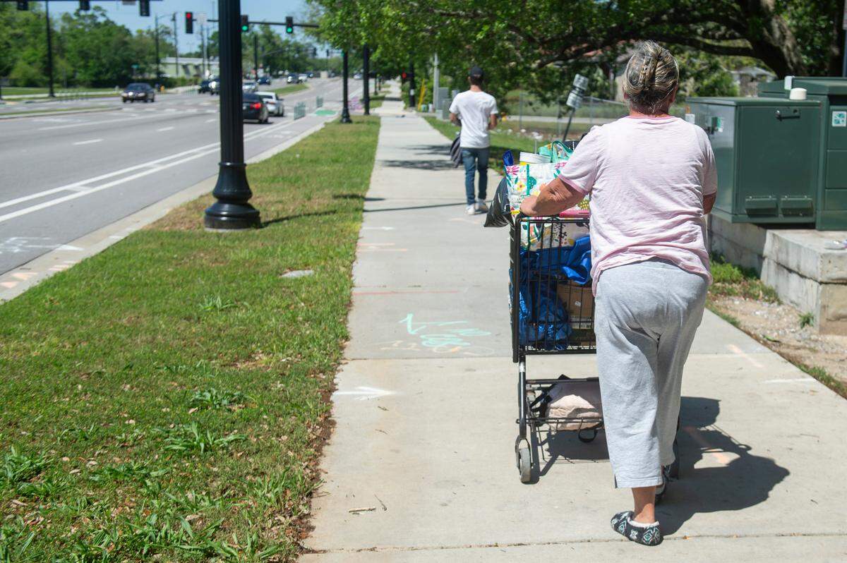 A woman experiencing homelessness walks along Division Street in Biloxi on Friday, April 11, 2025.