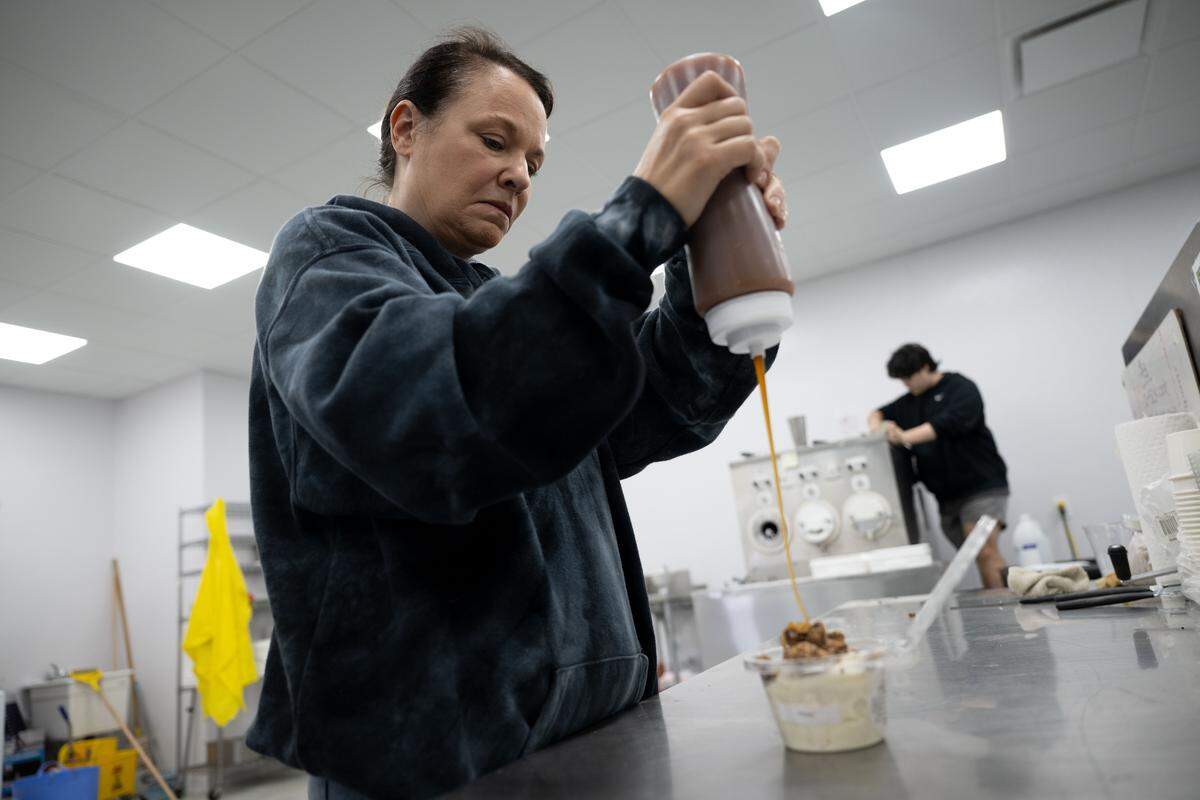 Marie Garbin pours caramel over a cup of frozen custard at the Quakes distribution center in Vancleave. The new factory is the first of a network of factories she plans to build across the country and internationally.