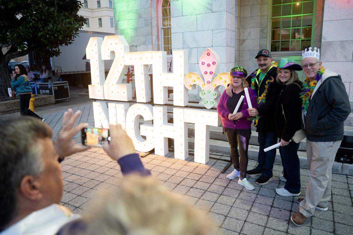 Parade attendees pose for photos in front of a sign during a 12th Night Celebration in Biloxi on Monday, Jan. 5, 2026.