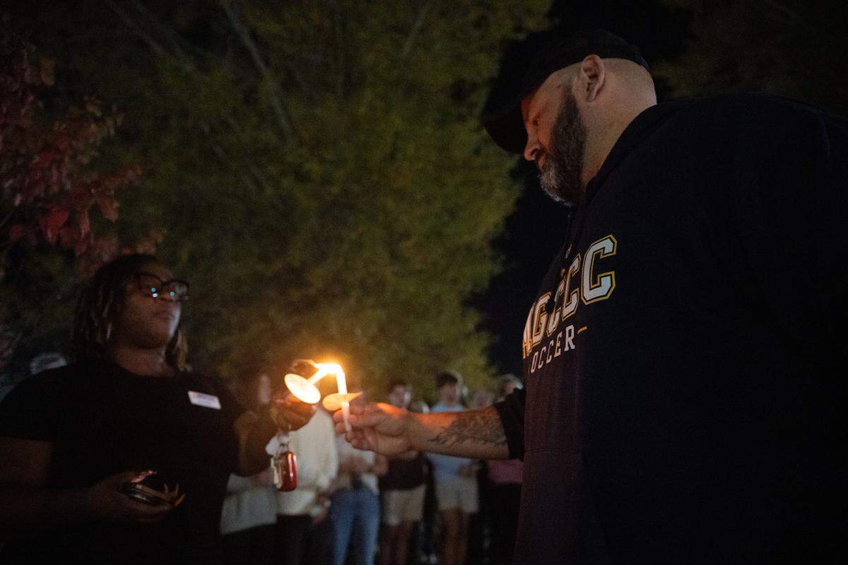 Josh Perry, Landon Perry’s father, lights the candles of attendees Thursday.