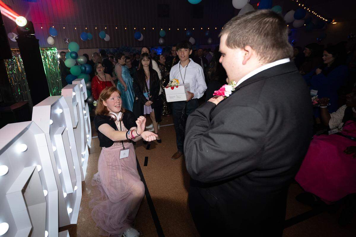 Mae Davis, left, pretends to propose to Anthony Payne, right, during Night to Shine at Woolmarket Baptist Church on Friday, Feb. 13, 2026.
