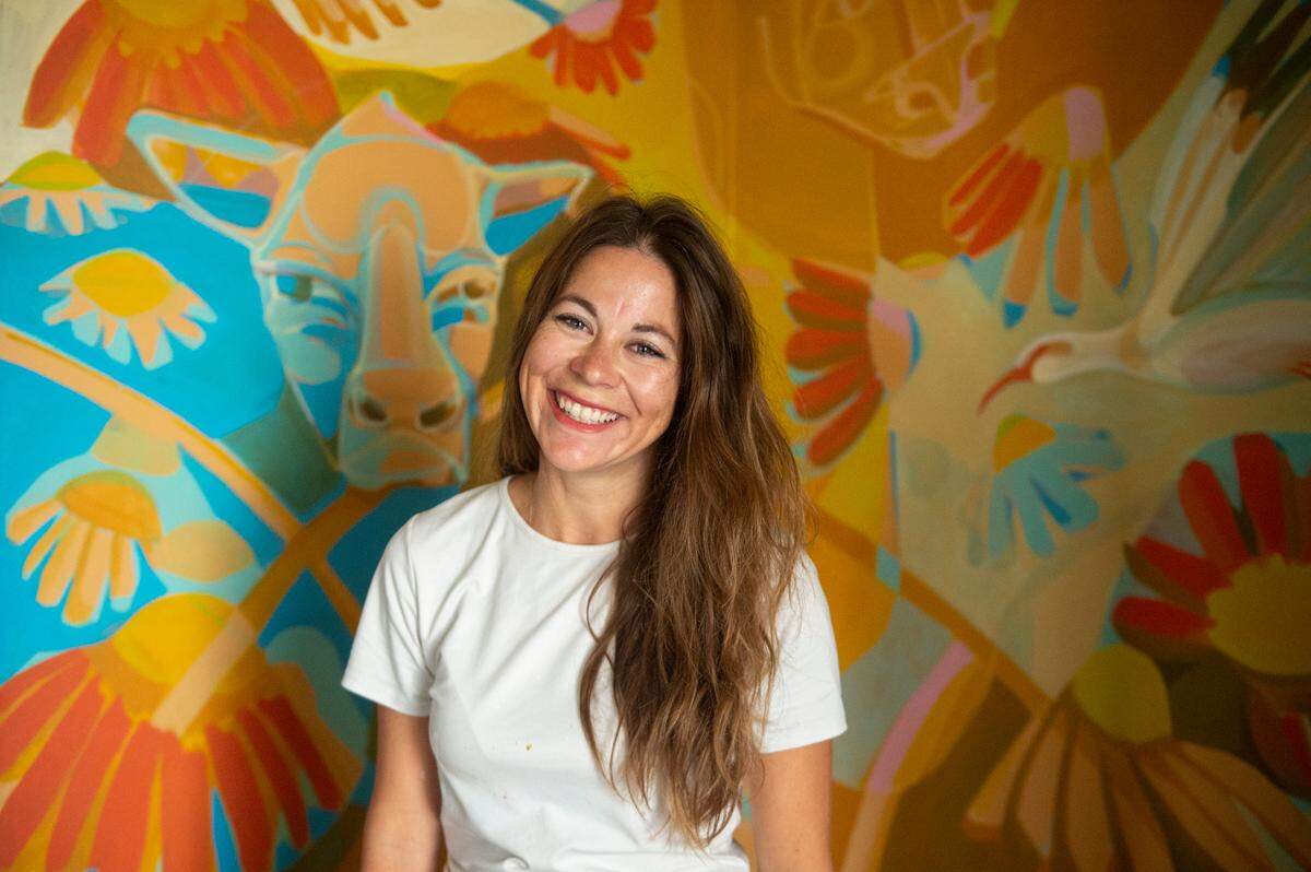 Julia Reyes stands in front of a mural she is working on at The Traveler, a new building at the Walter Anderson Museum of Art, in Ocean Springs.