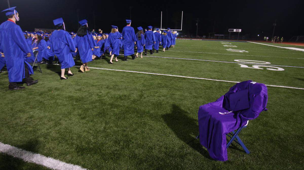 AMANDA McCOY/SUN HERALD 
 In memory of Glenda Rockwell, a student who succumbed to cancer in June, an empty chair draped with a graduation gown sits on Hancock High's Brett Favre Field during the graduation ceremony Thursday, May 19, 2016, in Hancock County.
