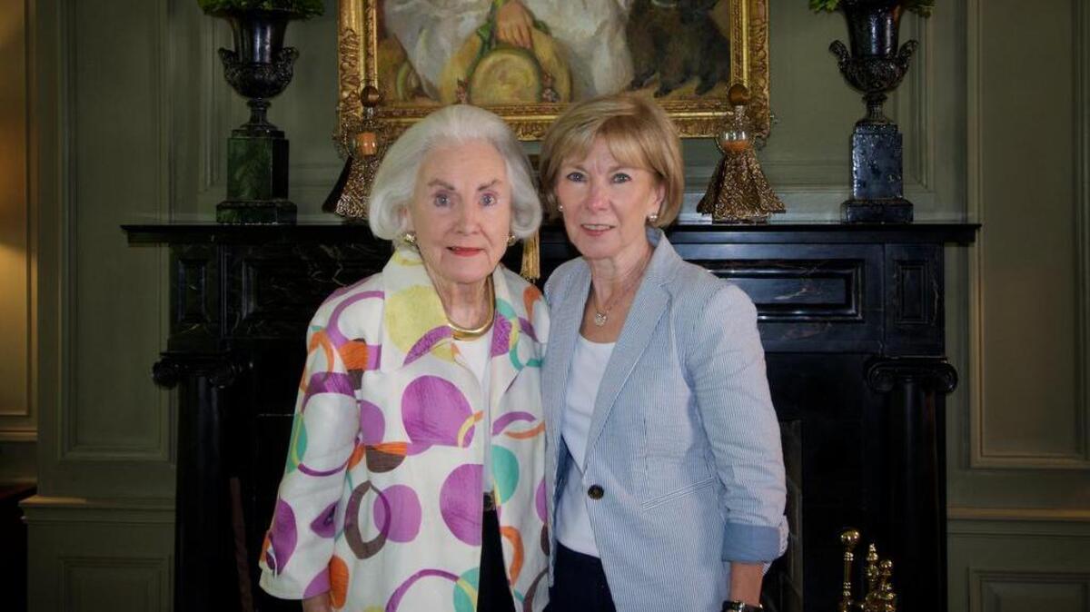 Genevieve Trimble with her daughter, Morrell Corle, standing under a portrait of Trimble as a young girl.