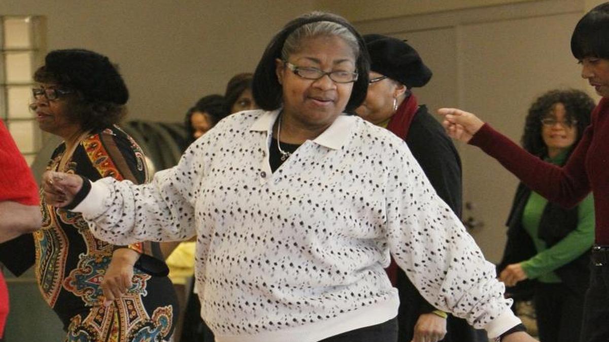 Elsie Colley dances with seniors learning line dancing in a class at the Lawton Community Center in Akron, Ohio.