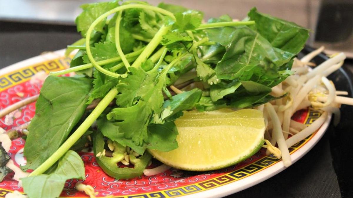 The garnish of vegetables and herbs allows you to customize your pho.