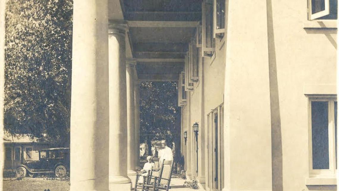 Dr. H.M. Folkes and wife enjoy the Gulf breezes from the veranda of their home.