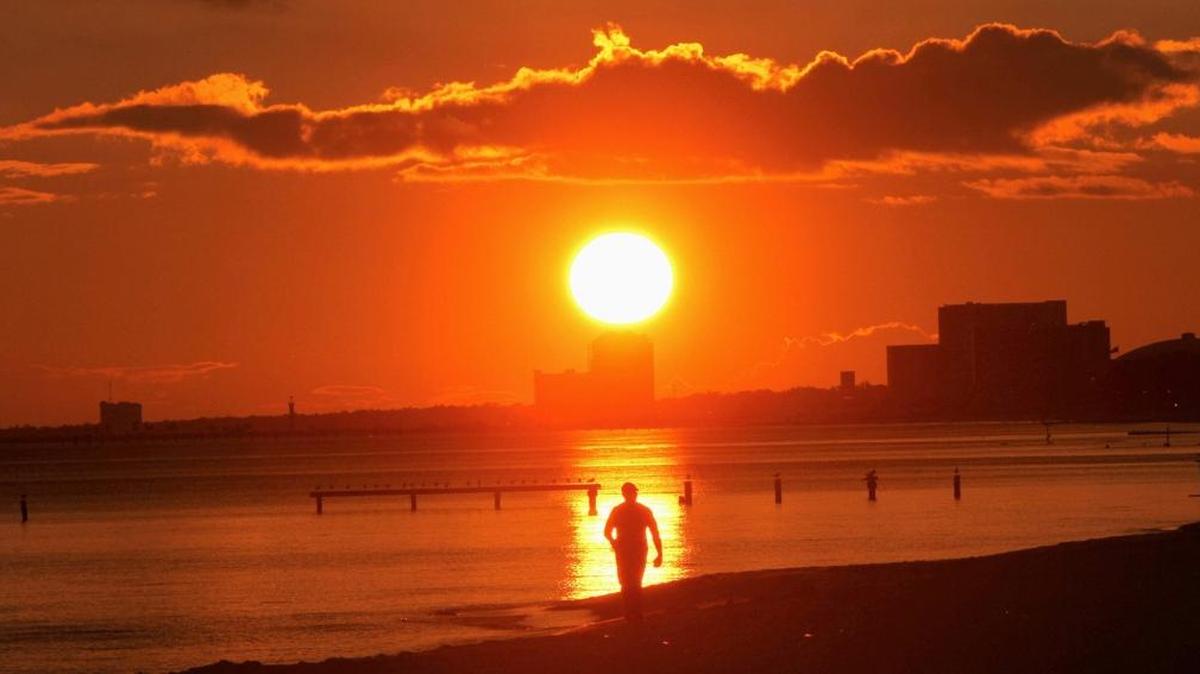 The setting sun provides a lighted backdrop for a person walking on the beach near Lighthouse Pier in Biloxi. Because of atmospheric changes, sunsets in the fall and winter tend to have more vivid shades of red, orange and yellow and even purple.