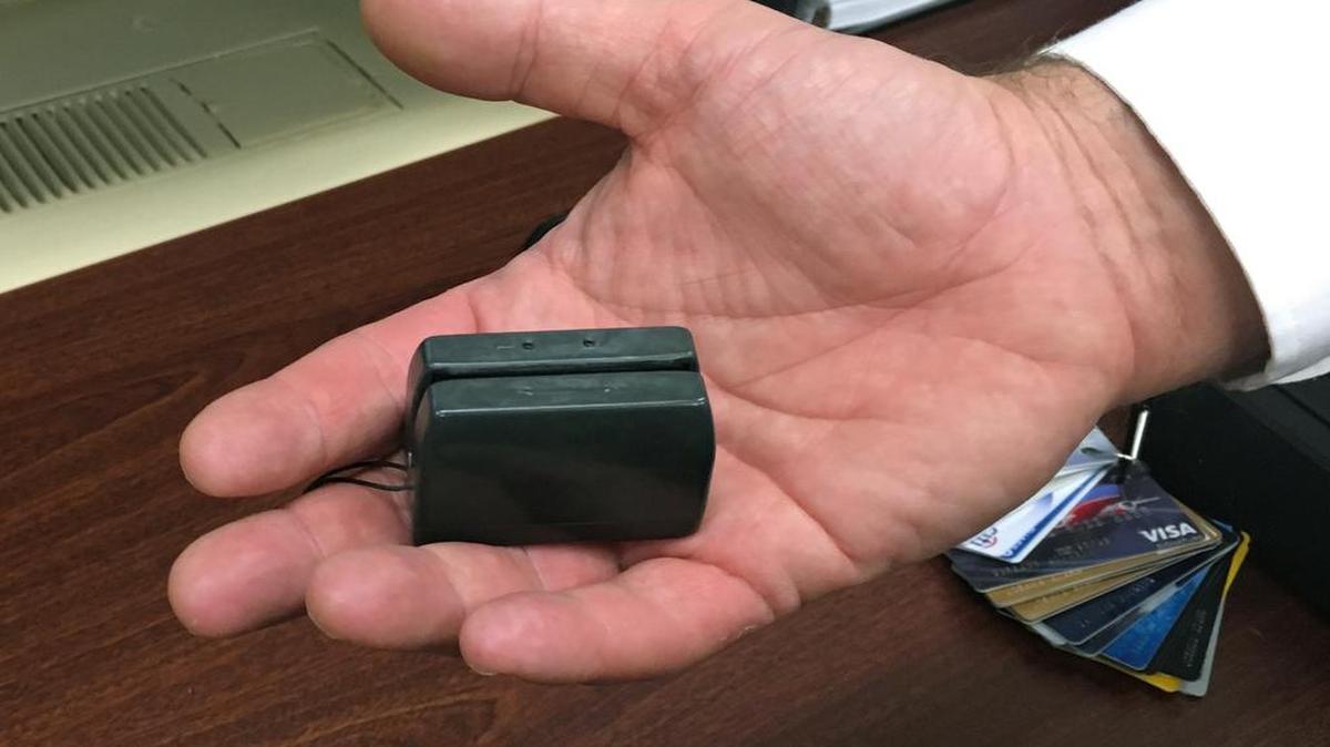 In this 2015 photo, a New York City Police detective holds a credit card skimmer that was used by a street gang to copy metadata from legitimate credit cards for use in the manufacture of counterfeit cards and possibly identity theft.