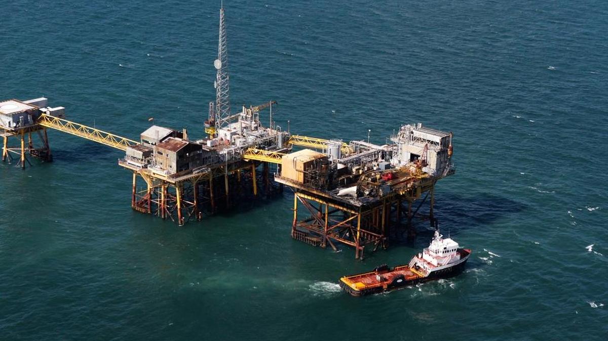 In this aerial photograph, a supply vessel moves near an oil rig damaged by an explosion and fire, Friday, Nov. 16, 2012, in the Gulf of Mexico about 25 miles southeast of Grand Isle, La. Four people were transported to a hospital with critical burns and two were missing.
