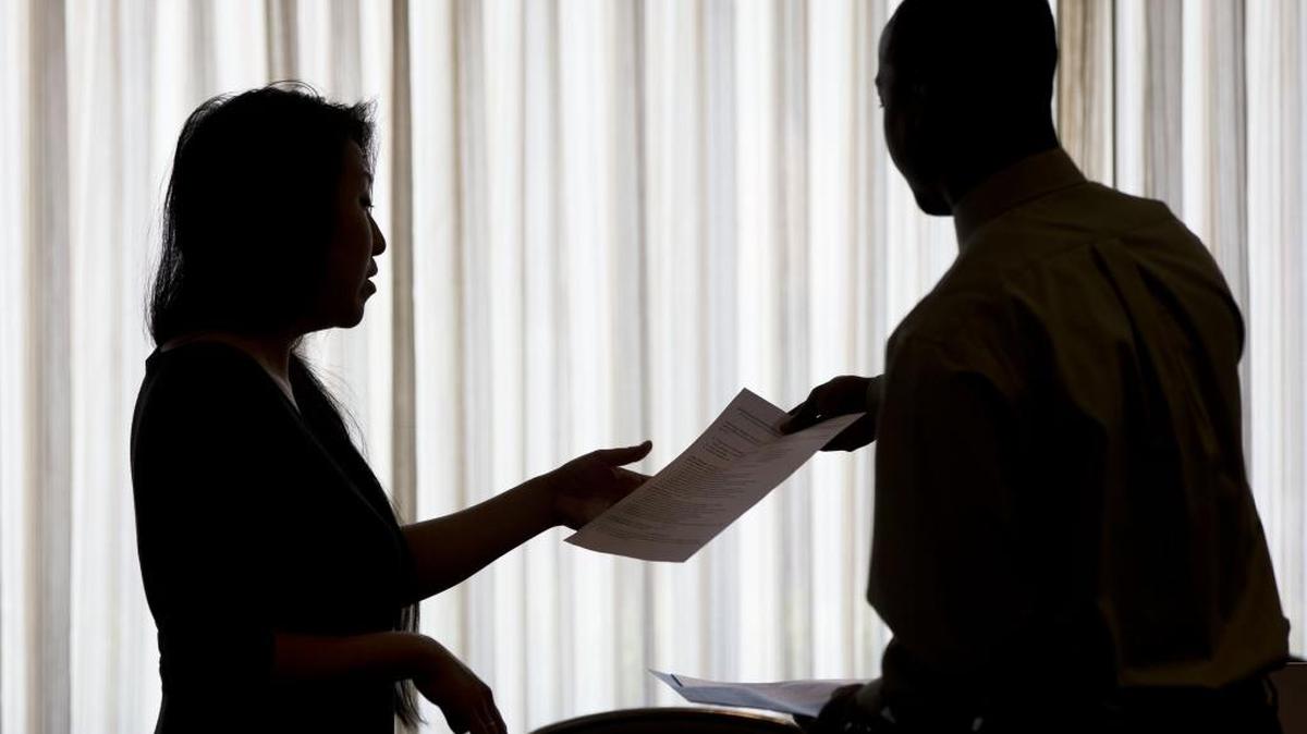 In this June 23, 2014, file photo, a recruiter, at left, takes the resume of an applicant during a job fair.