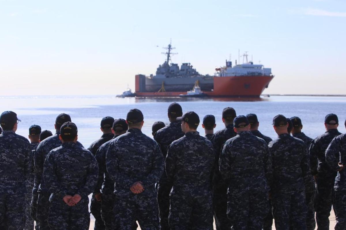 Crew members of the USS Fitzgerald wave to the ship as it comes in to Ingalls Shipbuilding for repairs on Friday, January 19, 2018. The destroyer was damaged when it collided with a container ship off the coast of Japan in June 2017.