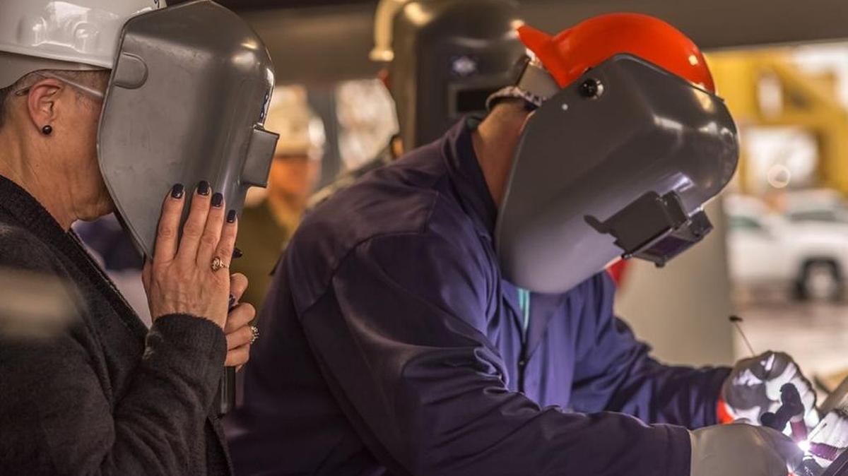 Jeremy Lally, a structural welder at Ingalls Shipbuilding in Pascagoula, welds the initials of ship sponsor D’Arcy Neller, left, onto the keel plate of the destroyer Frank E. Petersen Jr.